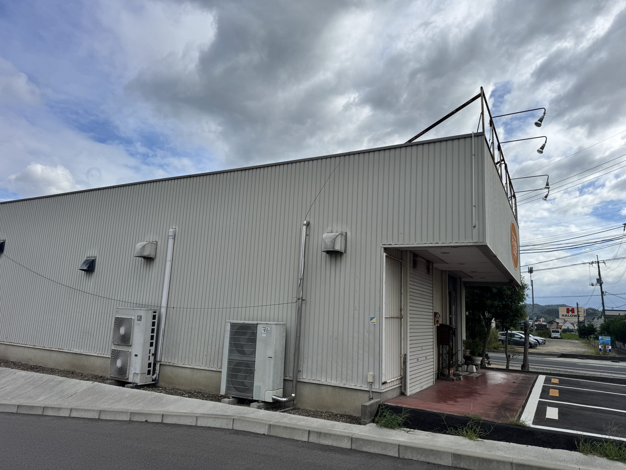 邑久町山田庄で撮影した建物の外観。縦張りの外壁、室外機、道路側のひさしと看板枠。